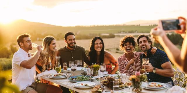 Woman taking picture of her friends at dinner party