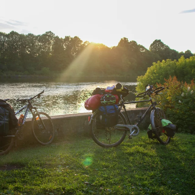 deux vélos dont un avec des sacs garés le long de l'eau