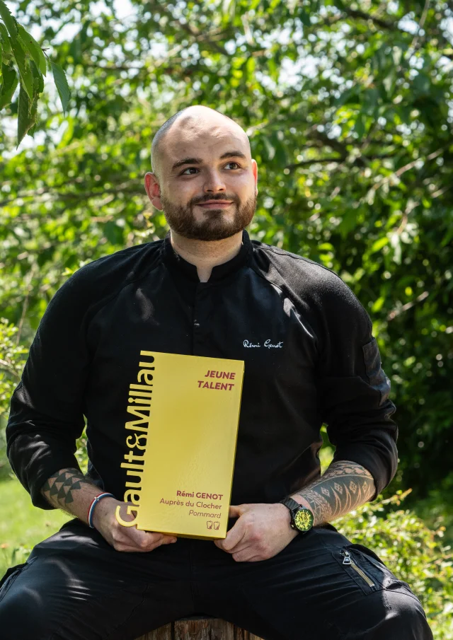 Chef assis en extérieur, trophé Gault et Millau en main